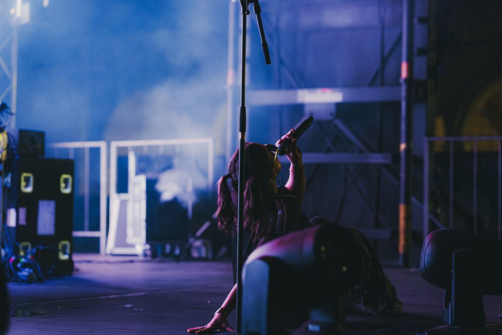 Silhouetted performer on stage with atmospheric blue lighting and fog effects during a nighttime show.