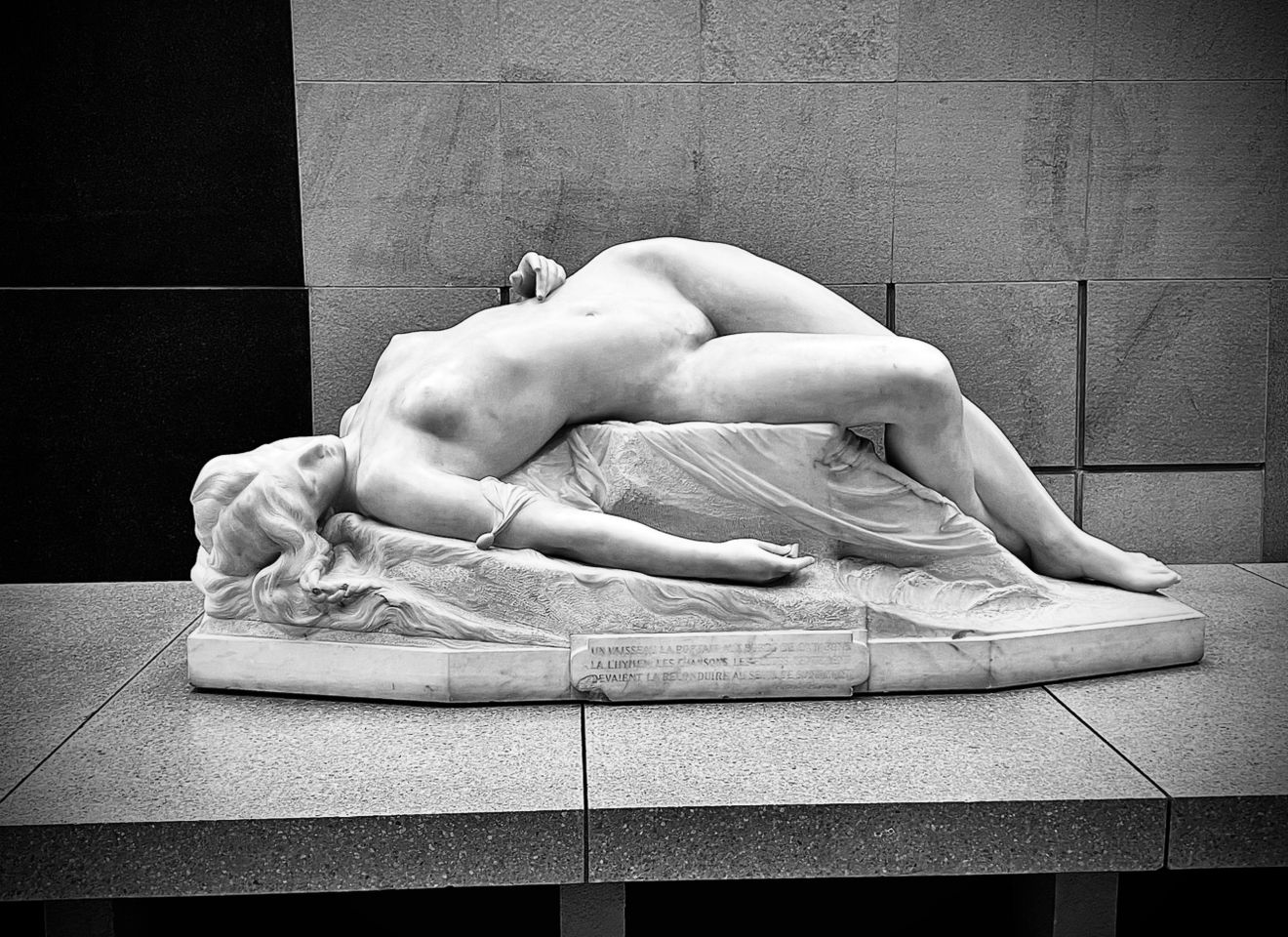 Black and white artistic photograph showing a nude figure lying on the ground in various graceful poses.