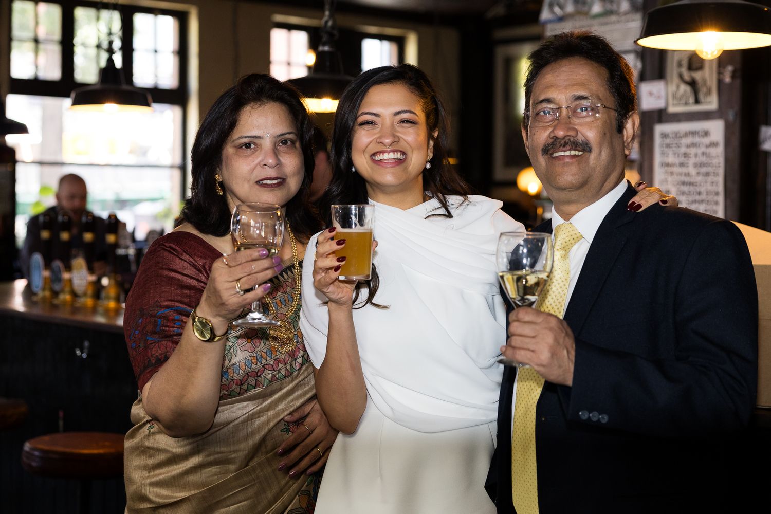 bride with her parents at wedding reception in pub