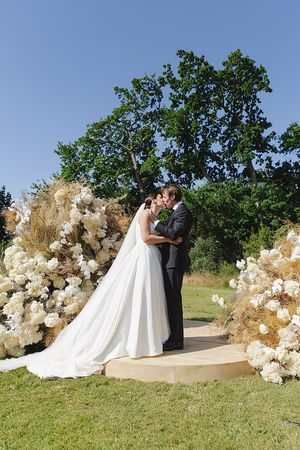 Bride and groom’s first kiss framed by textured florals.