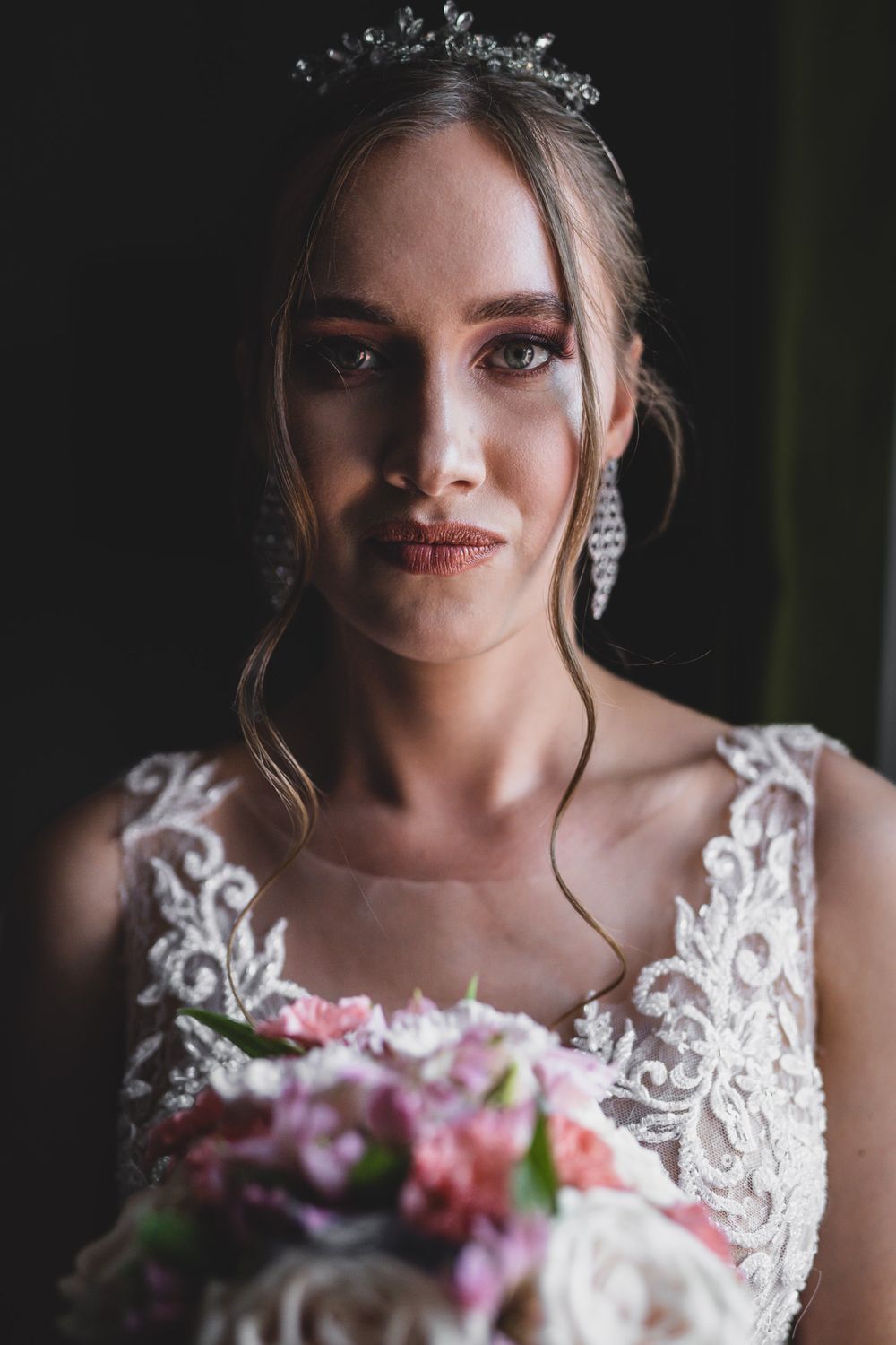 Elegant bridal portrait with delicate tiara and lace details in dramatic lighting.