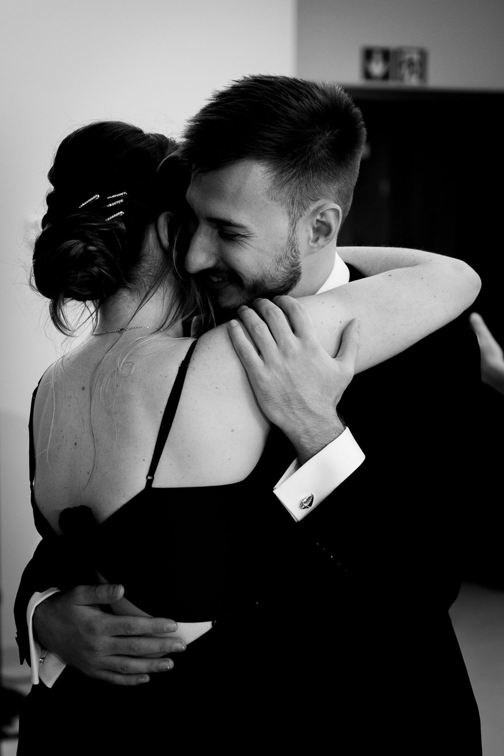 An intimate black and white photo capturing an emotional embrace between a couple.