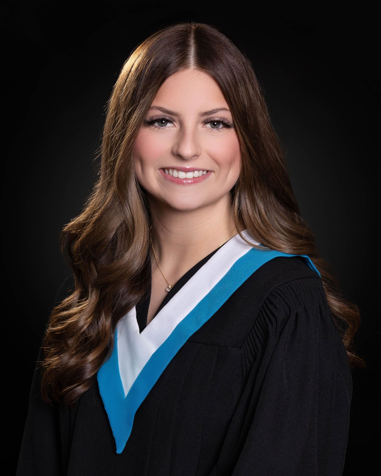 Senior studio portrait with gown against gray/black background