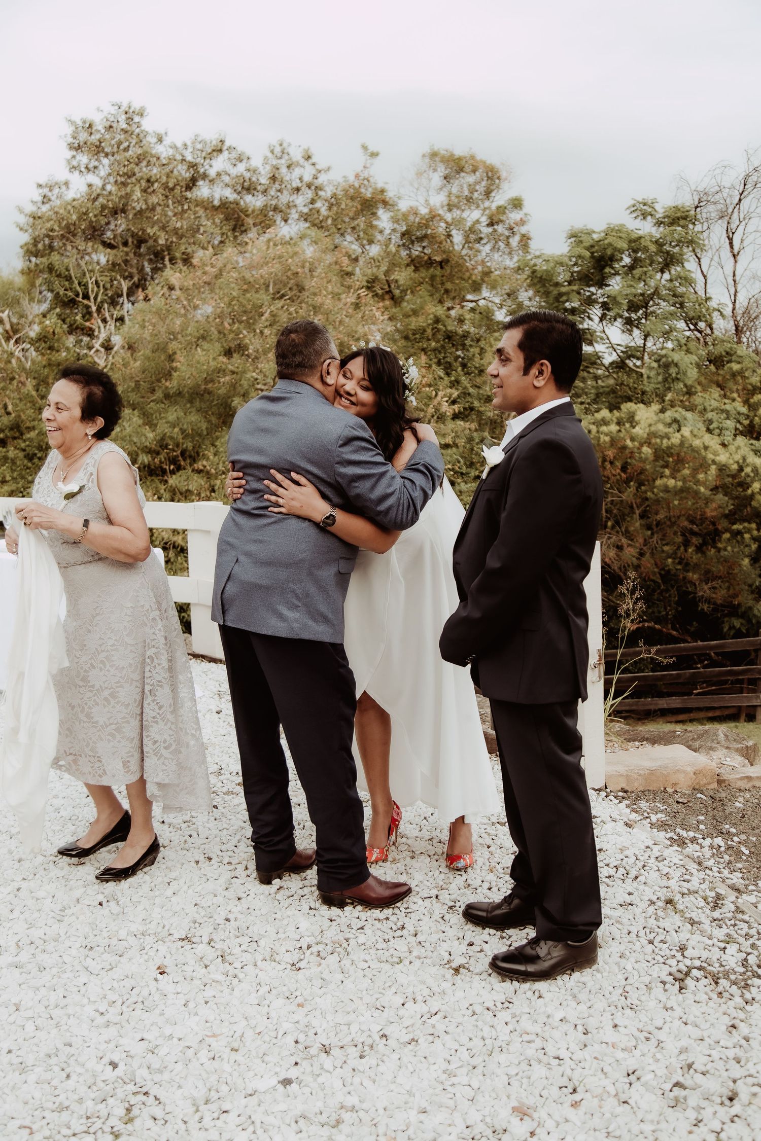 A sequence of playful dance steps on a gravel surface showing formal attire and flowing dress movement.