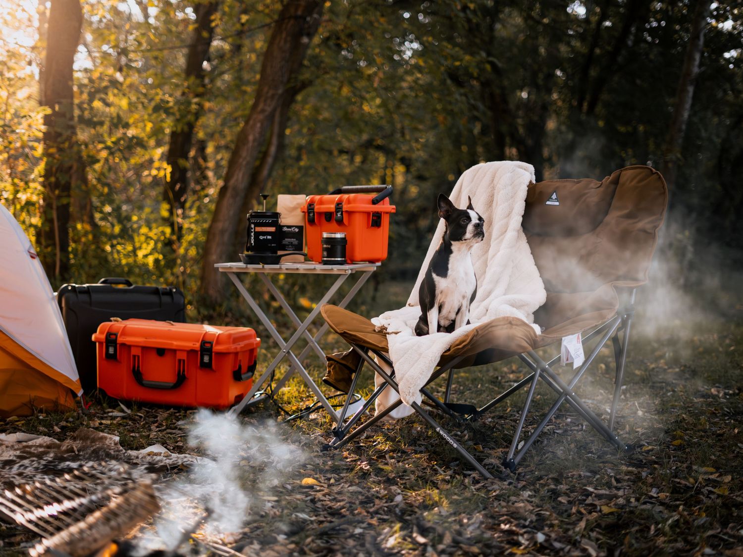Camping setup with white fabric and orange case creating atmospheric smoke in forest.