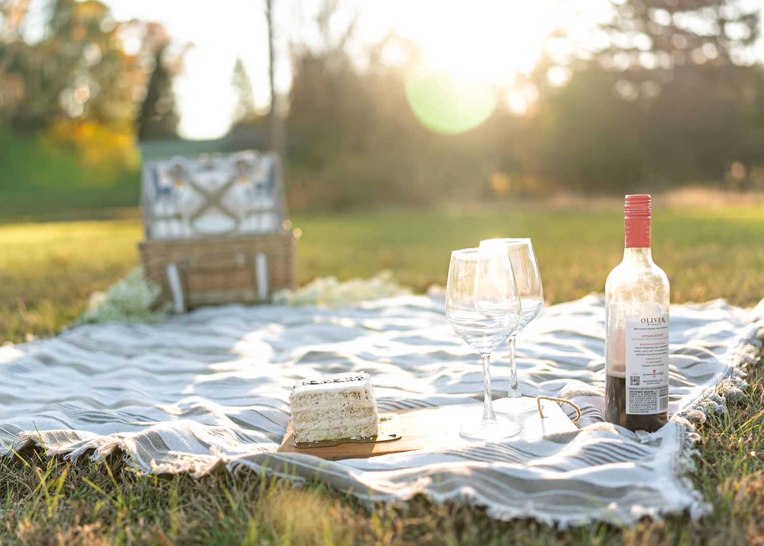 Sunset picnic setup with blanket and wine bottles in golden autumn light.