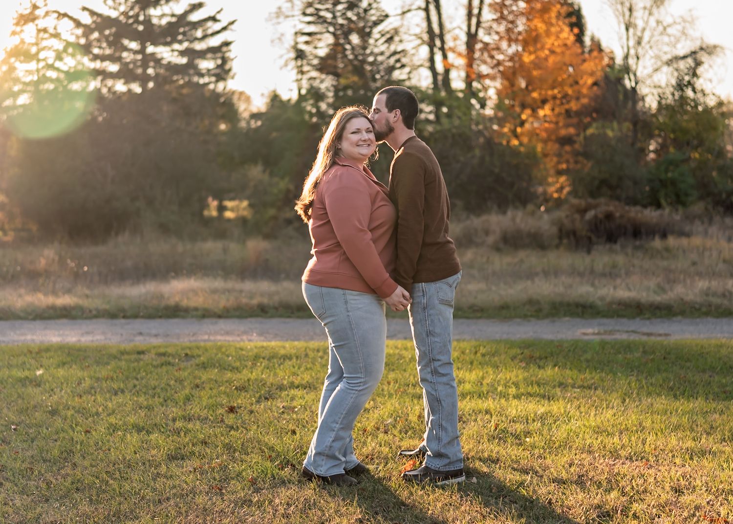 Couple walking together at sunset in autumn field with golden light.