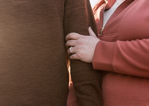 Close up of hands touching brown leather couch surface.