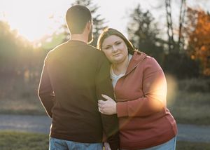 Romantic couple embraces in autumn sunset with golden light filtering through trees.