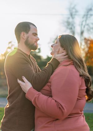 Tender moment between couple during sunset photoshoot in autumn setting.