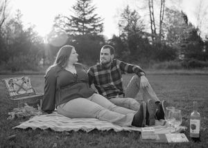 Black and white photo of couple laughing during outdoor picnic on blanket.