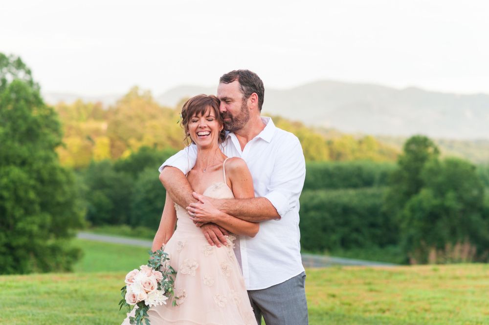 Casual outdoor couple portrait with rolling hills and greenery in the background.