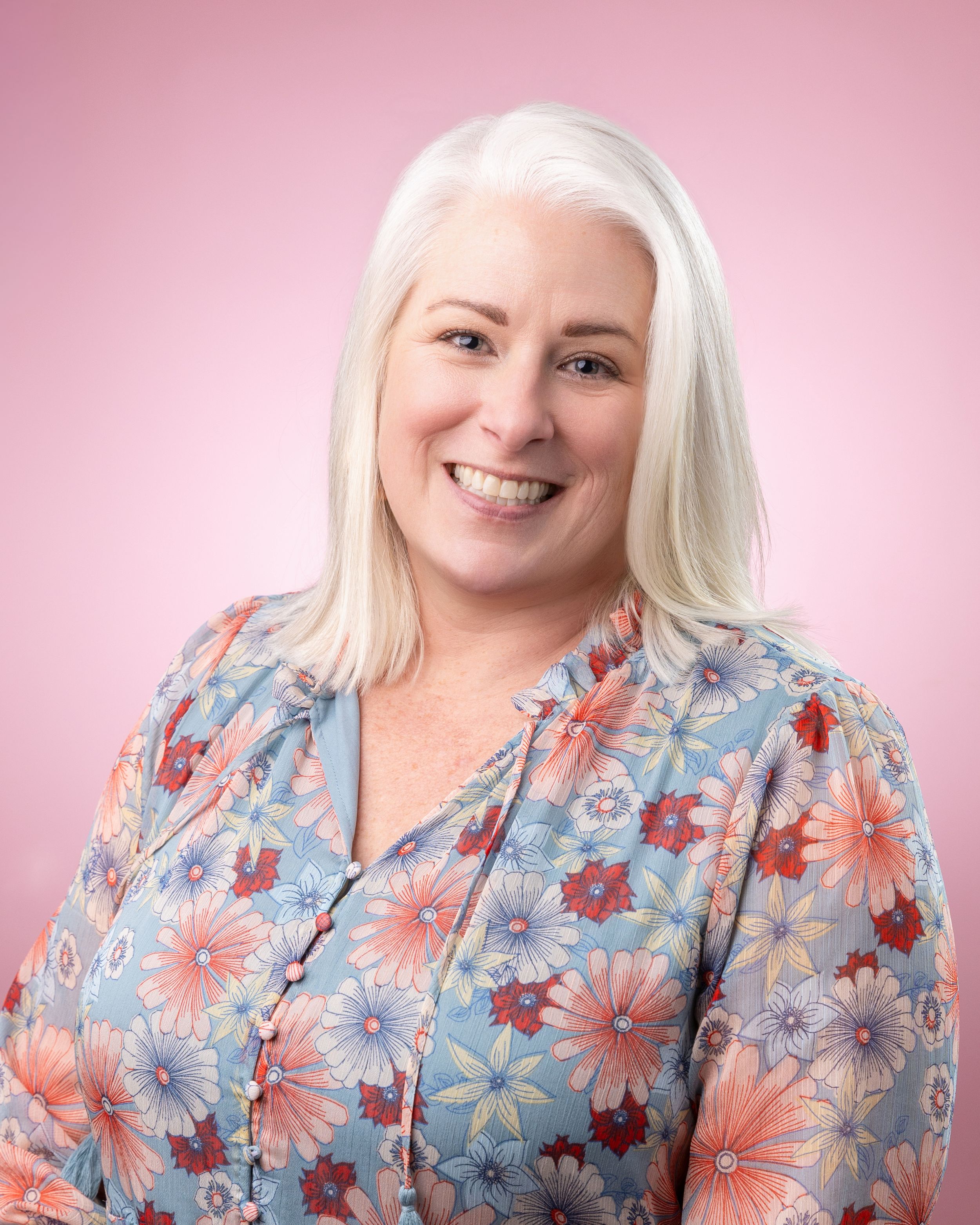 A floral print blouse in blue and coral tones is showcased against a pink background in a fashion photography series.
