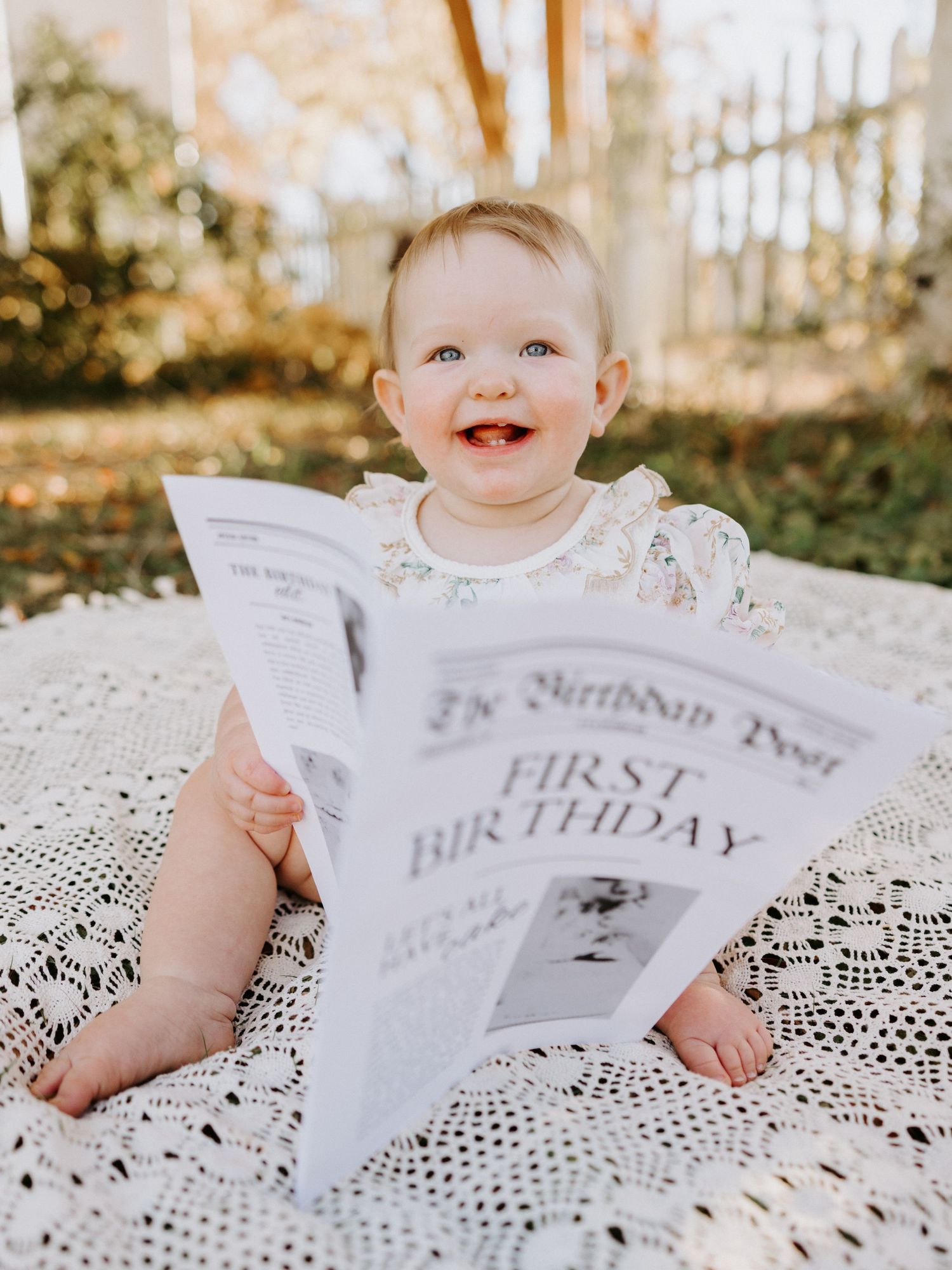 A baby sits on white lace while holding a newspaper with 'First Birthday' text visible in a series of milestone photos.