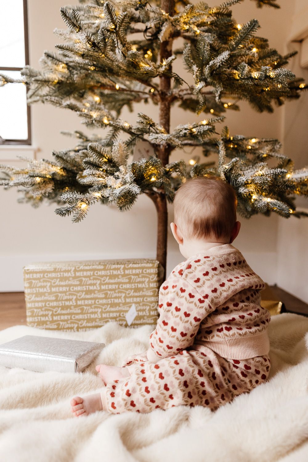 A baby looks at the family Christmas tree during their in-home photo shoot