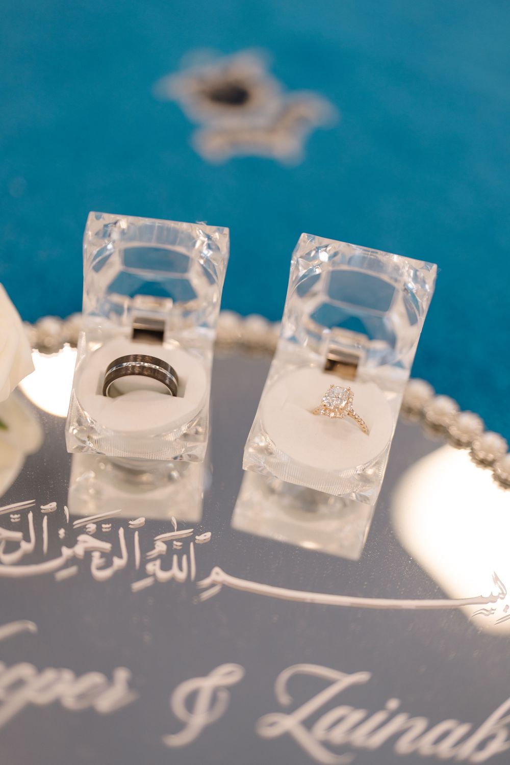 Islamic wedding rings displayed in crystal boxes on mirrored tray engraved with names Yaques and Zainab.