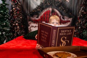 Christmas themed still life with vintage books and red fabric against dark wooden background with twinkling lights.