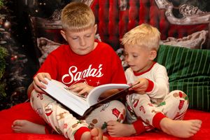 Children in matching Christmas pajamas read books and enjoy snacks during holiday storytime.