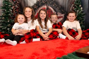 A group poses together on a red couch with festive holiday decorations and greenery in the background.