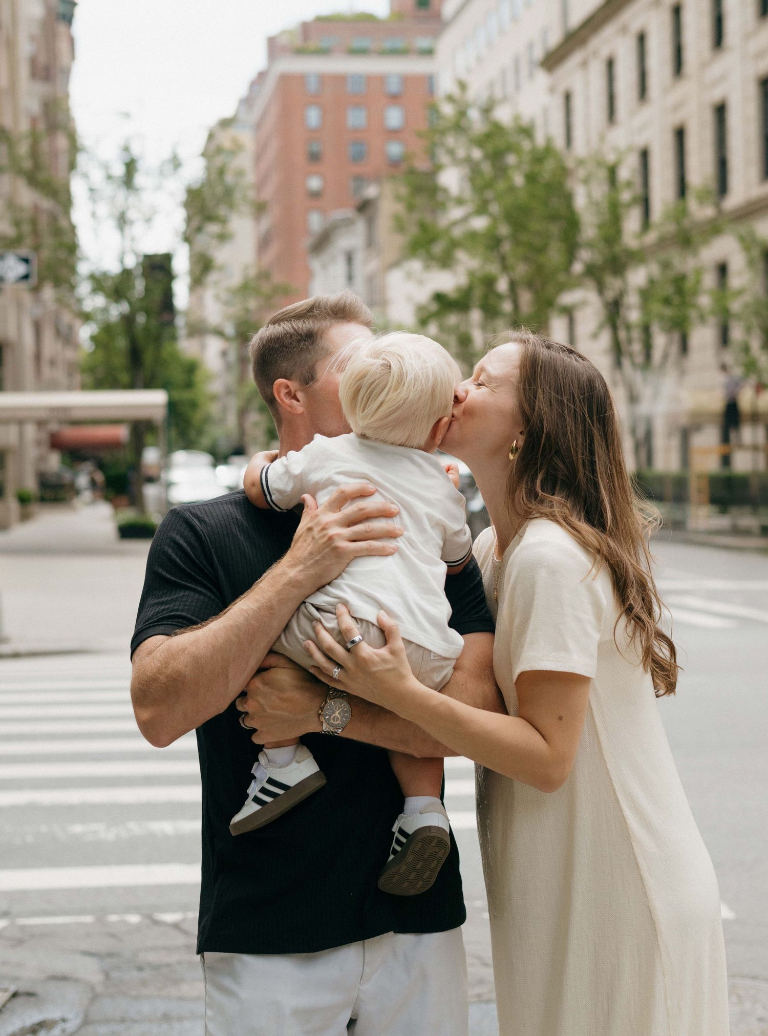 Family shares tender moments together on urban street during lifestyle photoshoot.