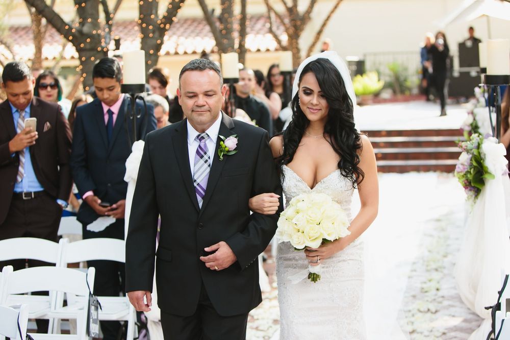 Wedding party members in formal attire stand together during an outdoor ceremony.