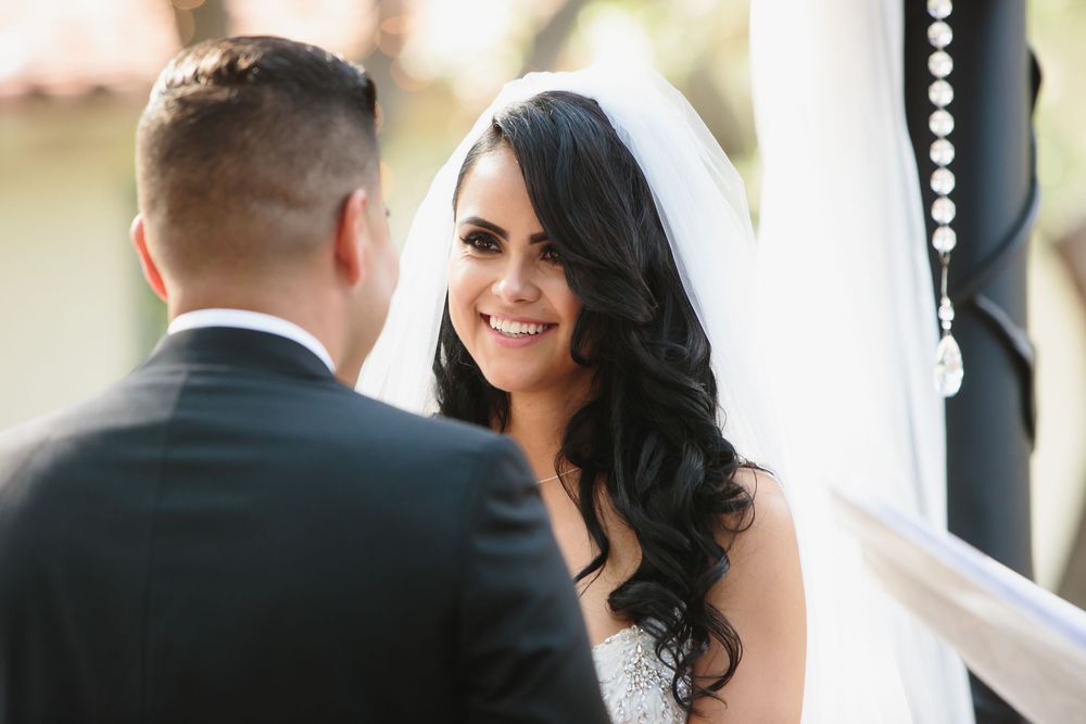 Happy couple sharing intimate moments during their wedding ceremony at a bright outdoor venue.