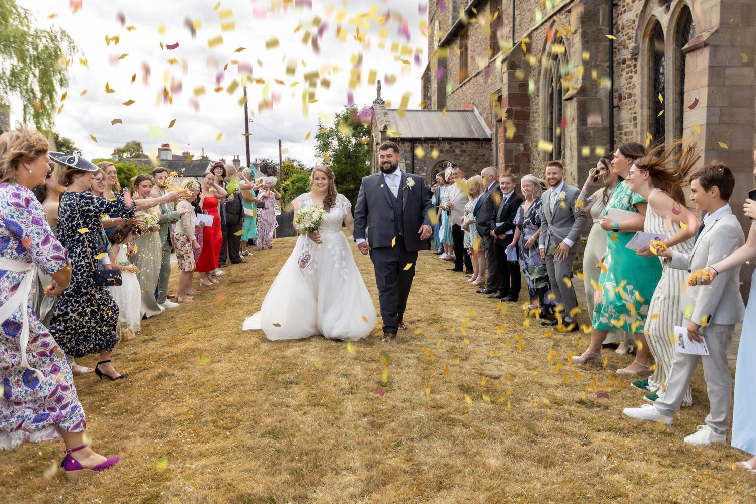 Wedding guests shower newlyweds with rose petals as they exit a church on their special day.