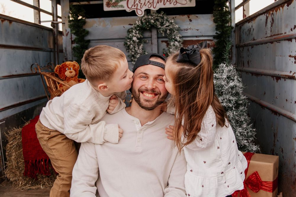 A warm family moment in a rustic Christmas-decorated trailer with greenery and lights.