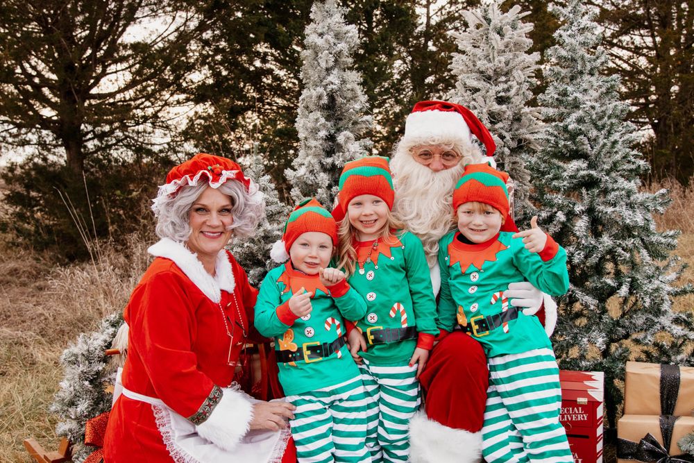 A cheerful holiday group photo with matching green and white striped outfits against snowy trees.
