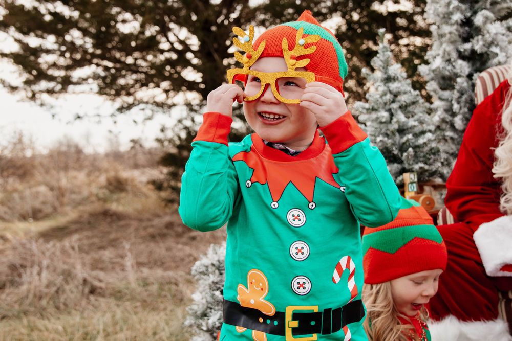A festive elf in green adjusts their antler headband during a Christmas photo session.