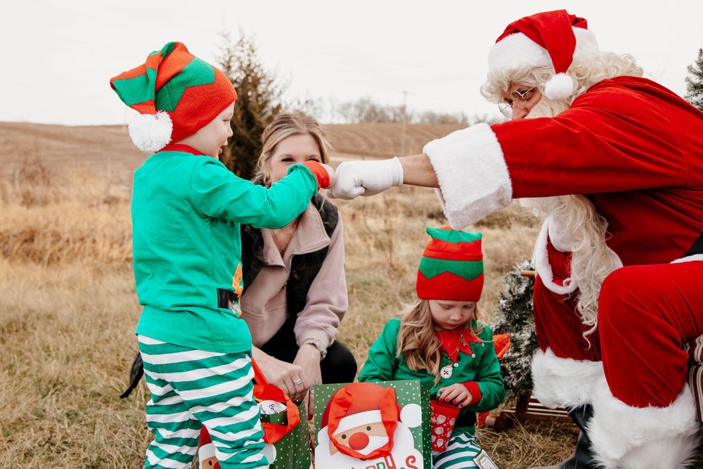Festive characters in elf costumes interact during an outdoor Christmas photo session.