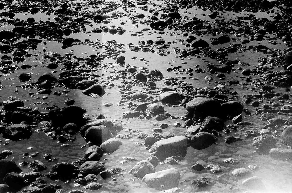 Black and white aerial footage shows a sequence of explosions and debris across a landscape.