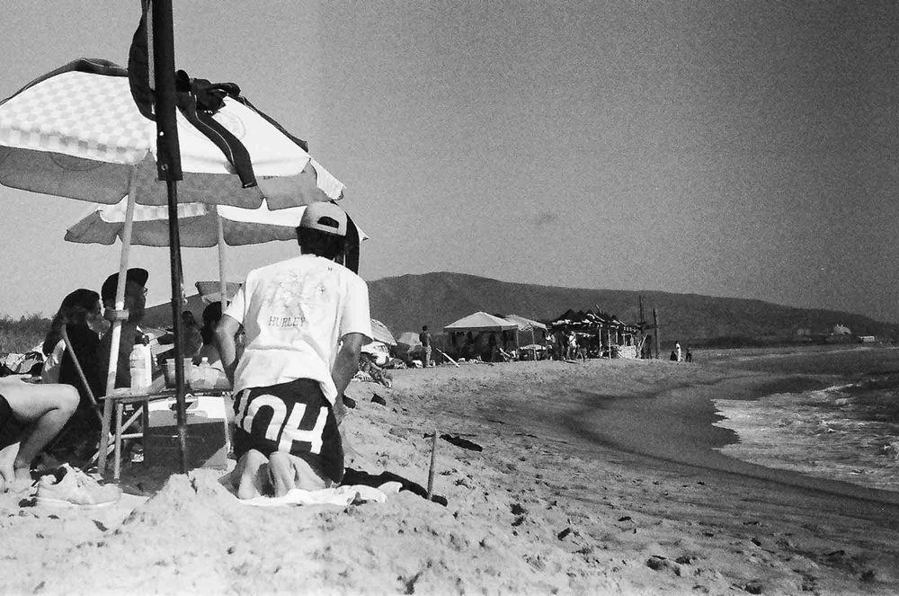 Vintage black and white photographs of a beach scene with umbrellas and people enjoying the seaside.