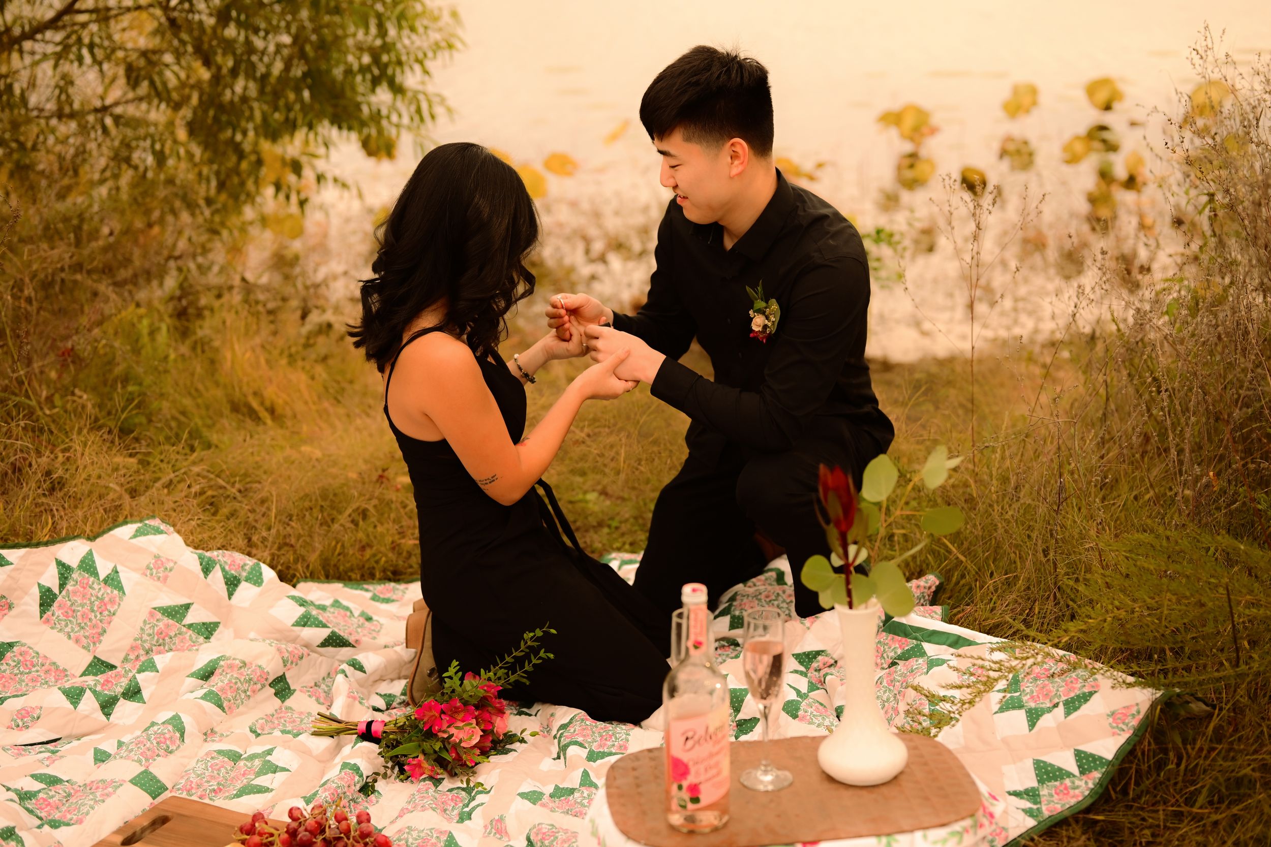 A couple enjoys a picnic date at a table decorated with flowers during golden hour.