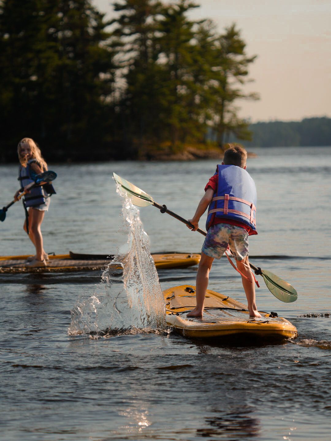 Two paddleboarders splashing water while enjoying a sunset lake adventure.