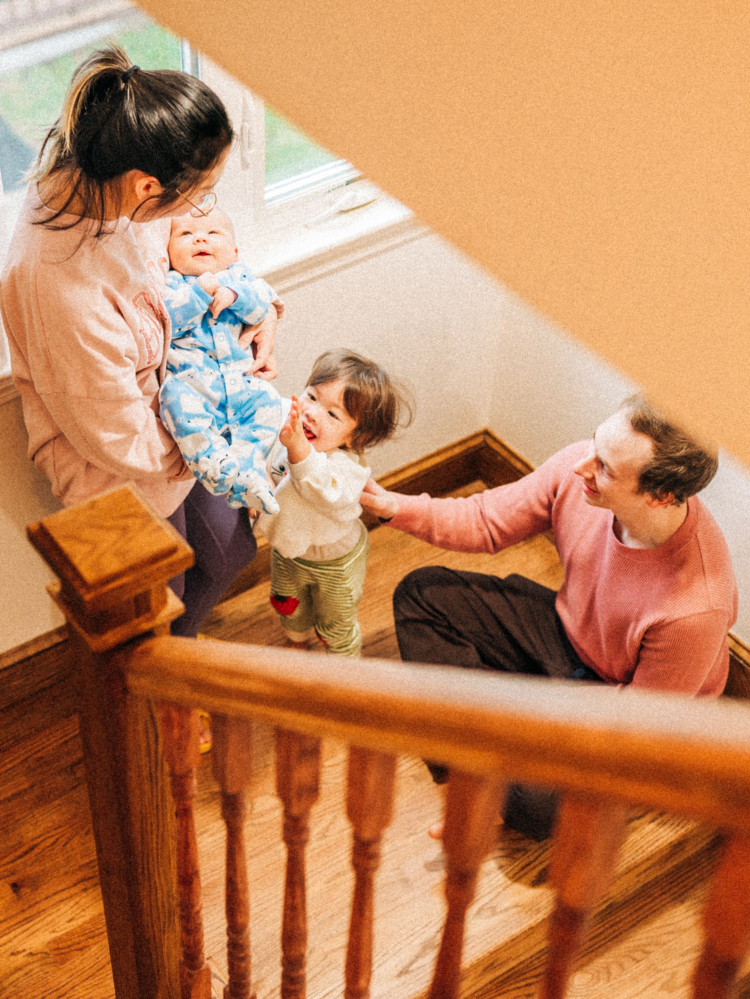Family spending time together on wooden staircase in home with natural lighting through window.