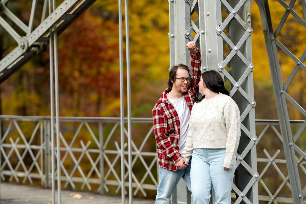 Young couple sharing a tender moment on a steel bridge in fall.