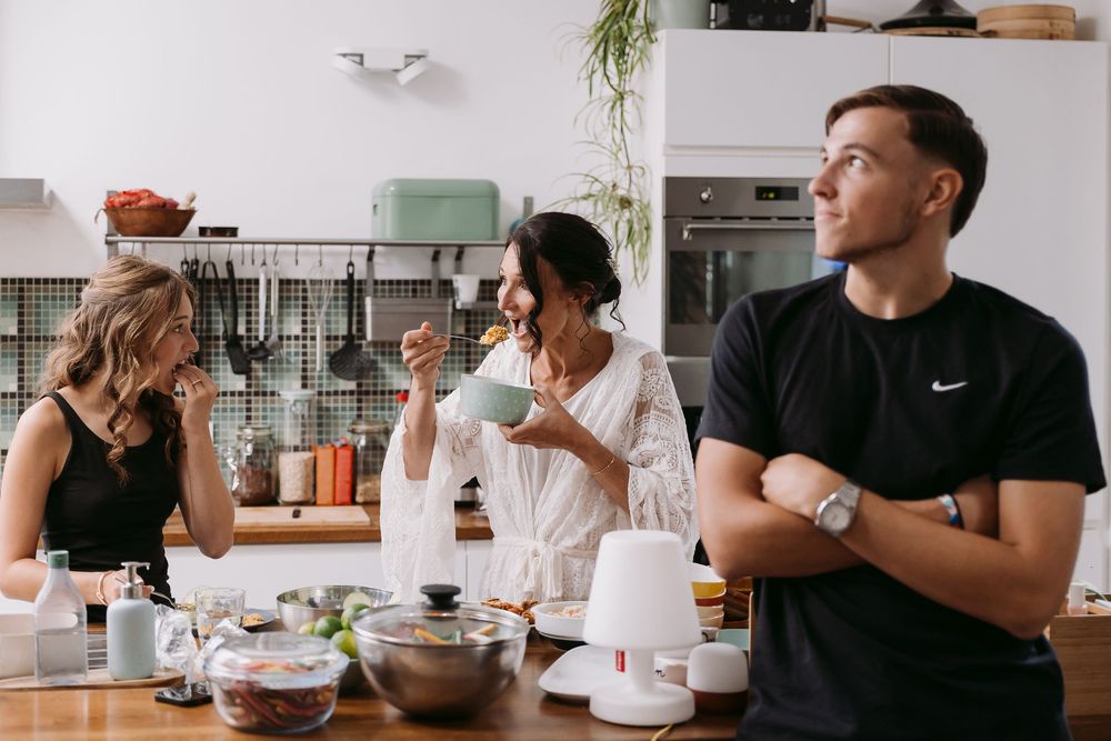 Bright modern kitchen with white cabinets and people gathered around the counter.