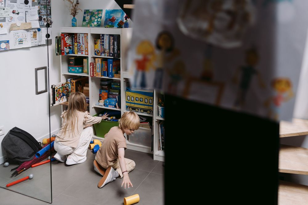 Child playing with toys near bookshelf in home setting.