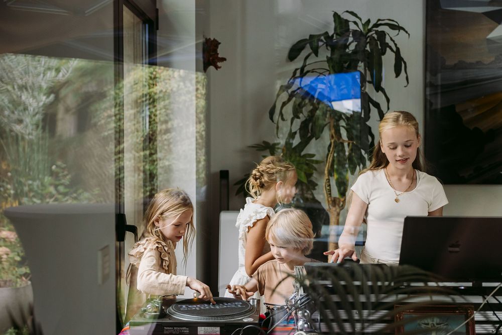 Group of people gathered around a table in a bright modern home setting enjoying a casual gathering.
