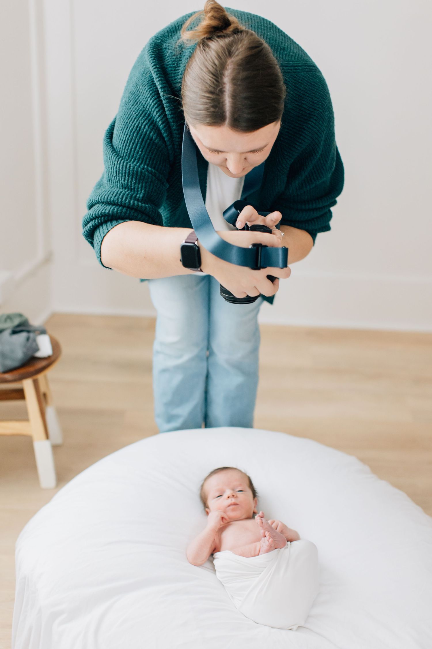 Photographer capturing overhead shots of newborn baby on white backdrop.