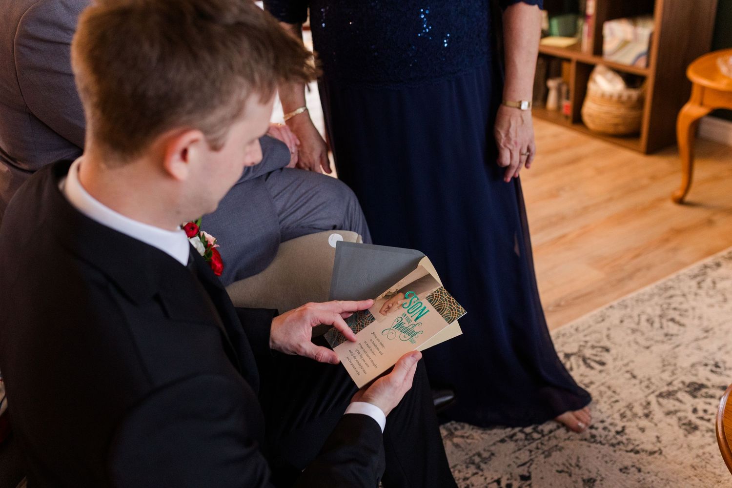A person holds a dollar bill while seated in an elegant room with wooden floors and oriental rugs.