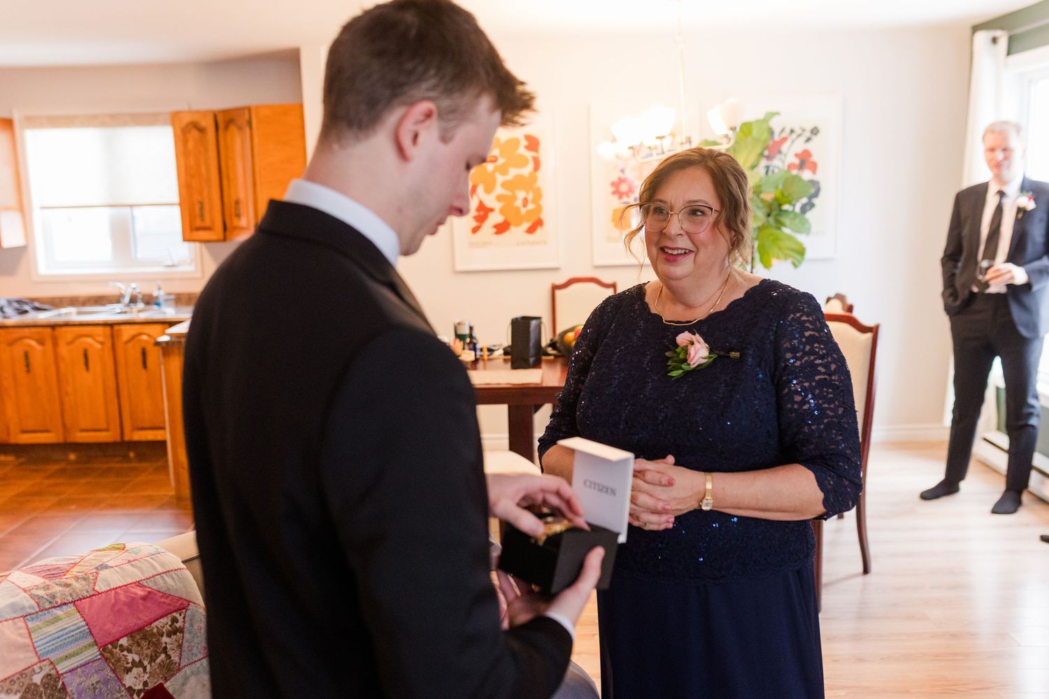 People interacting in a bright room with orange walls and wooden kitchen cabinets in the background.