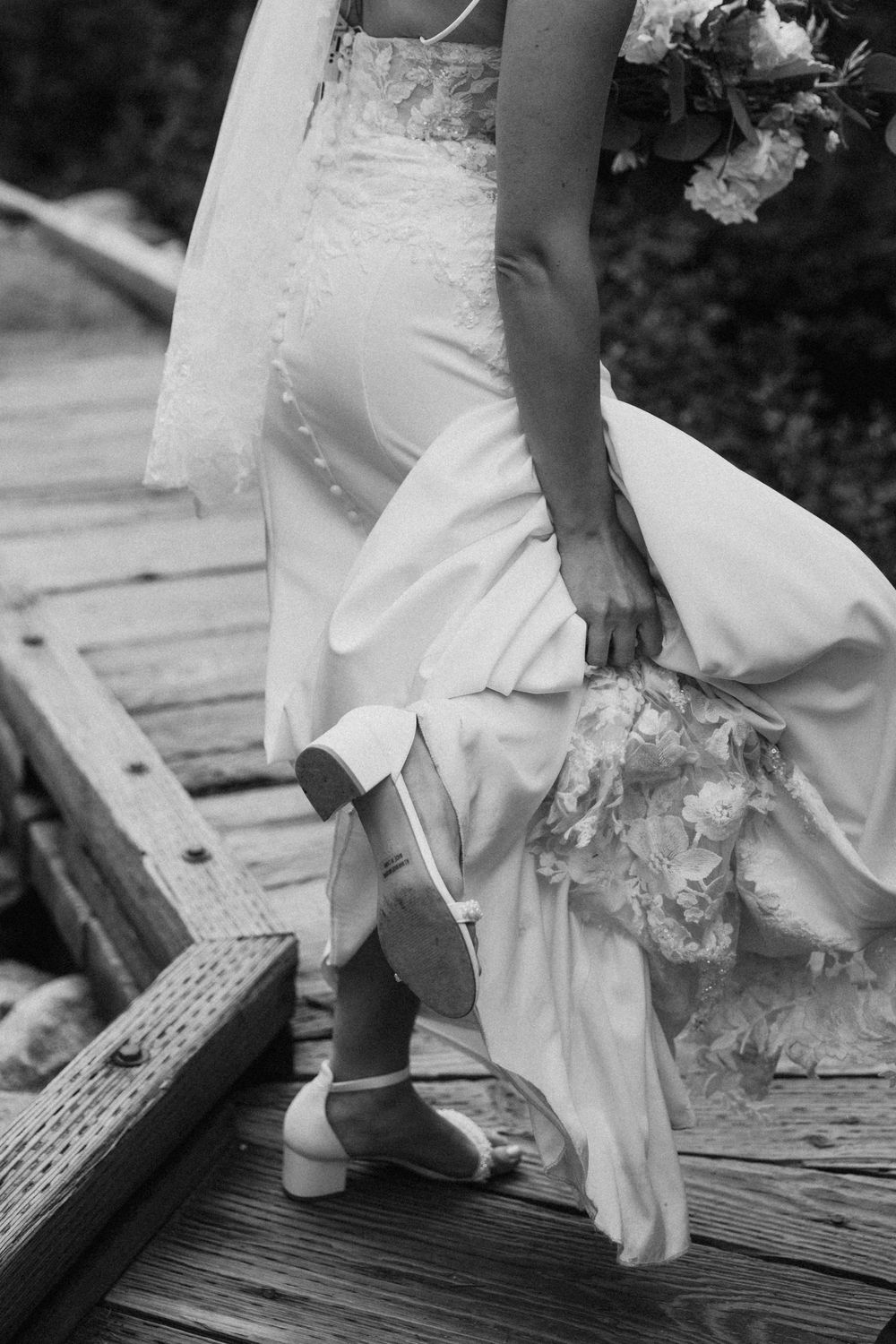 Black and white detail shots of a bride's feet in white shoes walking across wooden planks.