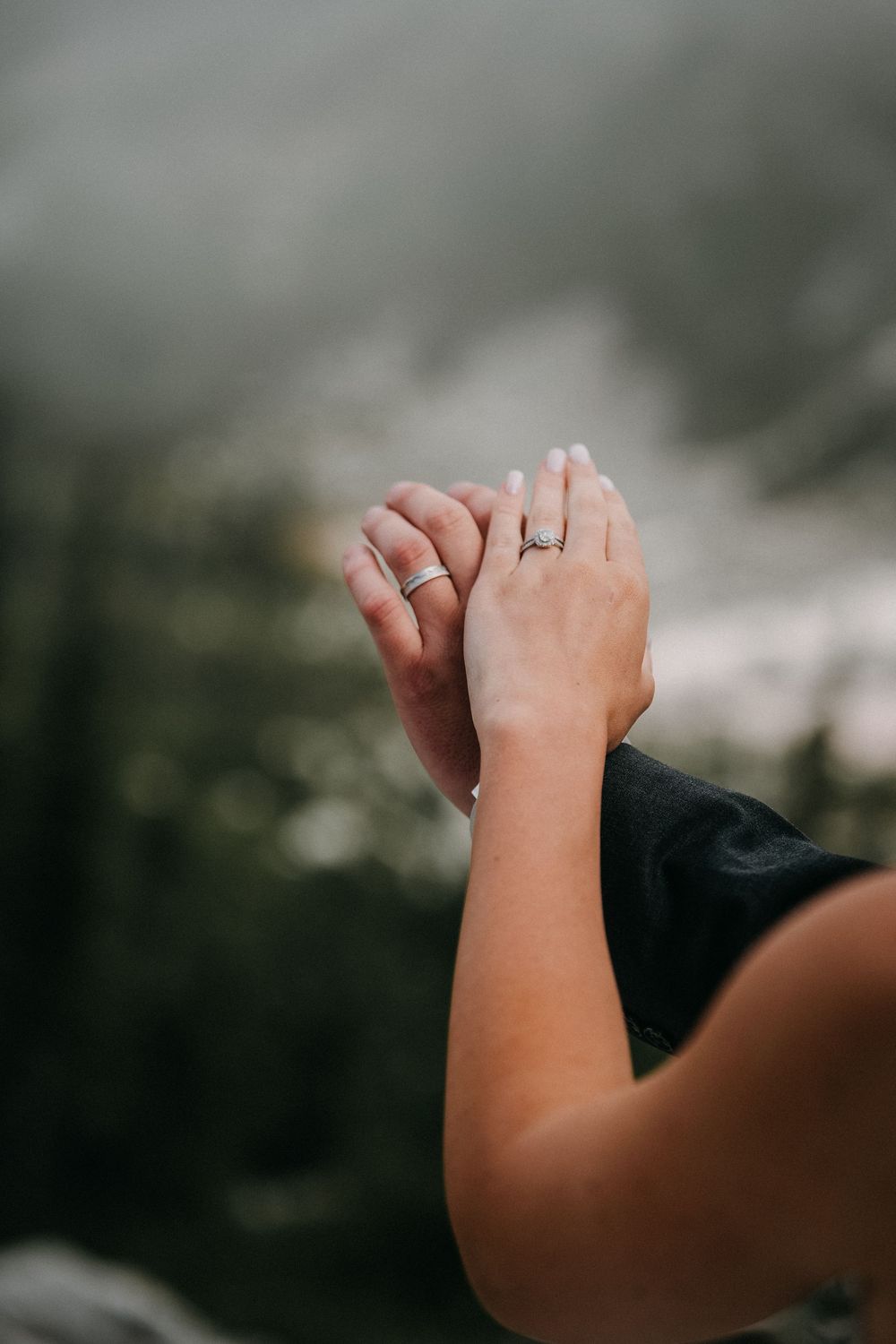 Close-up shot of clasped hands showing a wedding ring against a blurred background.