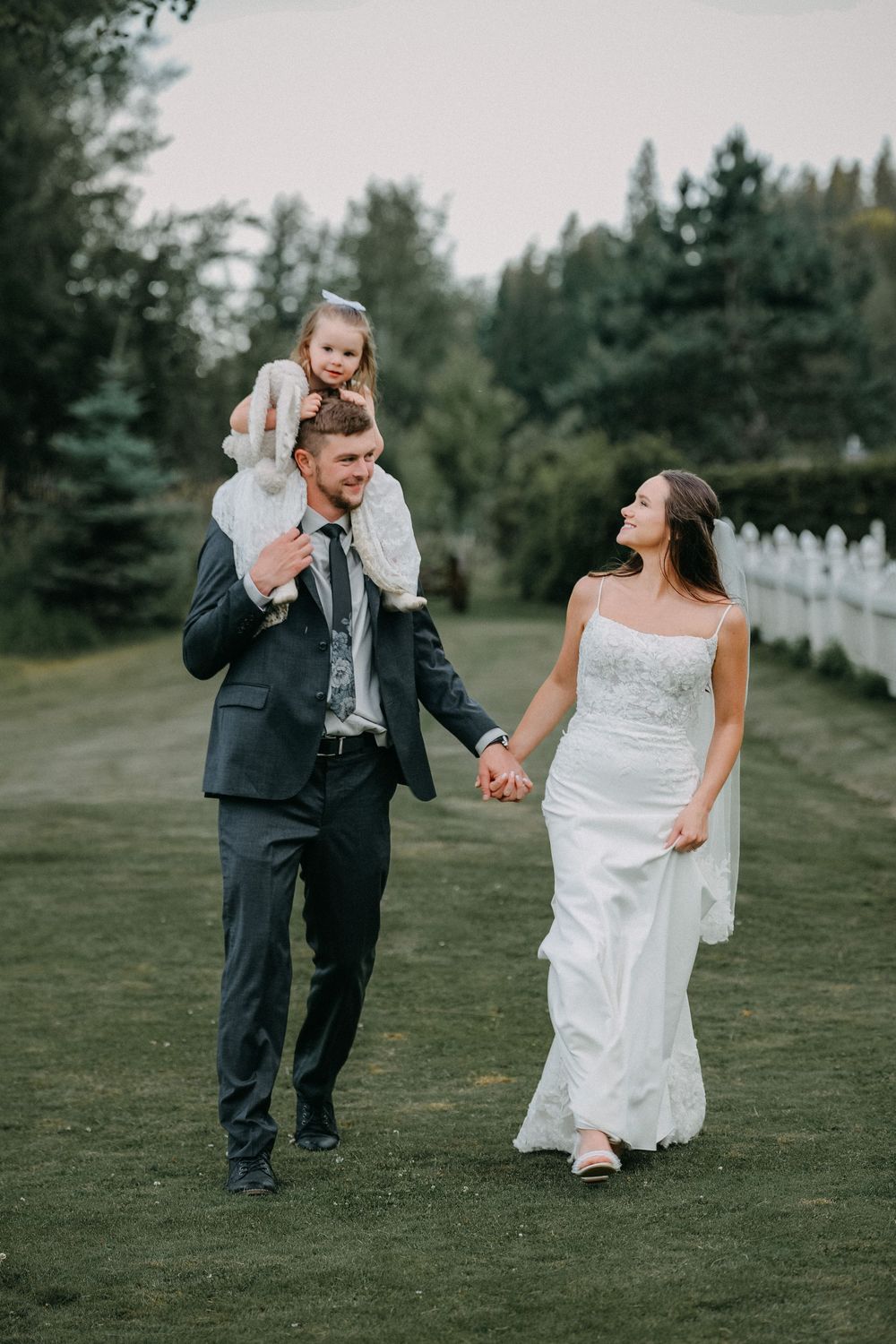Playful wedding couple runs and laughs together on a grassy hillside.