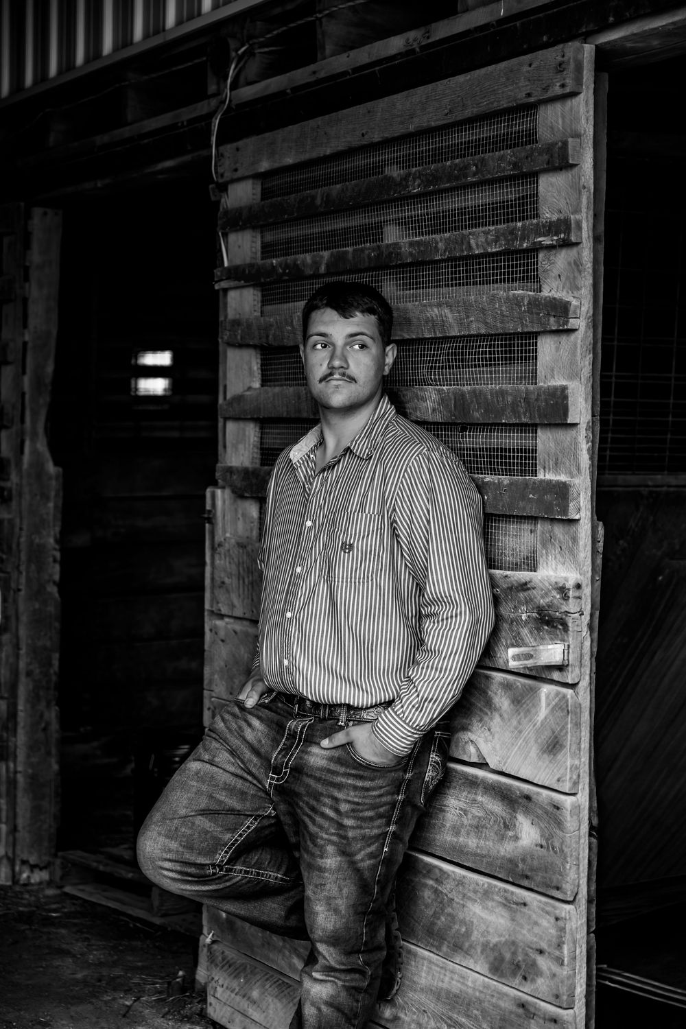 A series of black and white photographs showing a person in striped shirt and jeans standing near wooden structures.