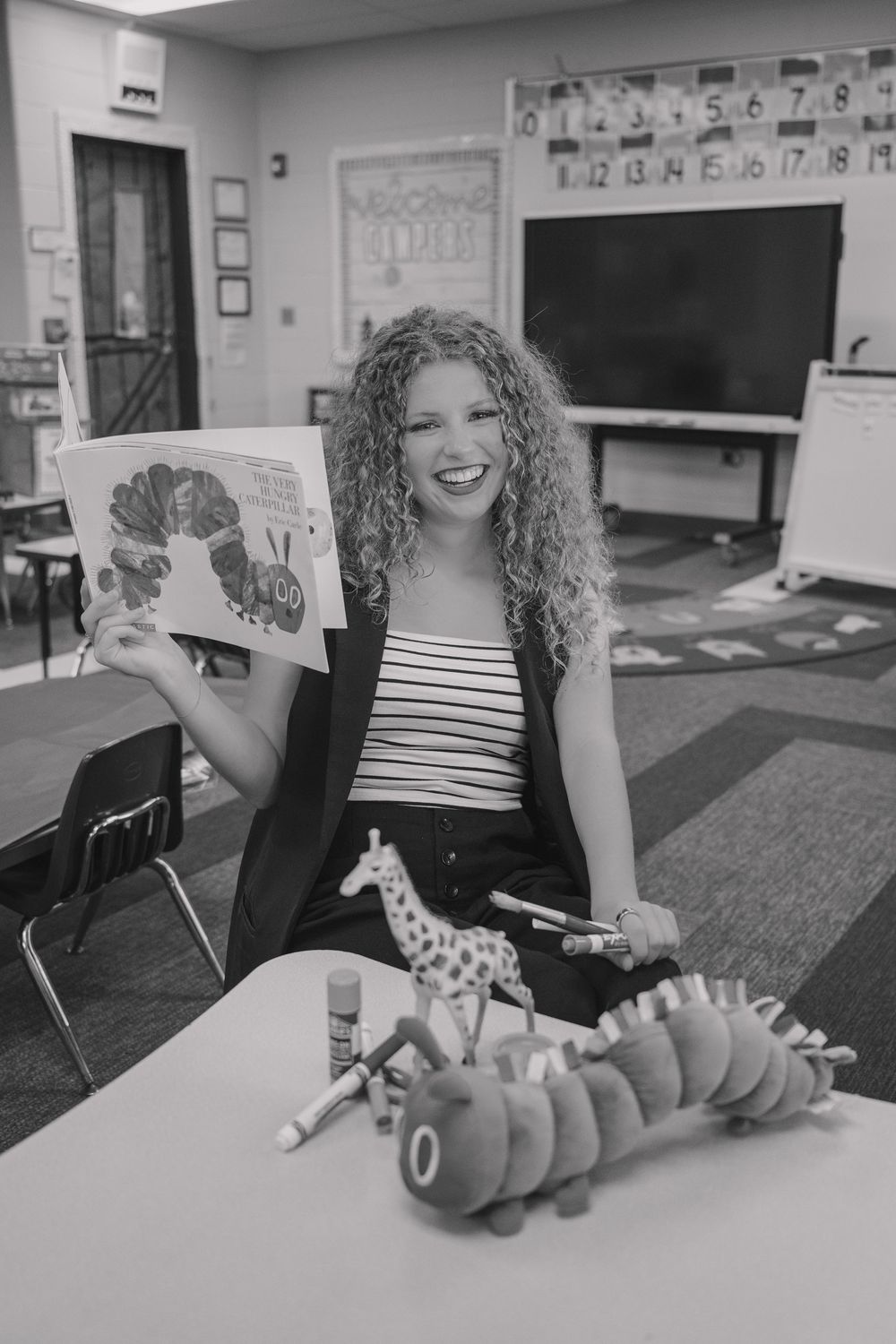A sequence of black and white photos showing hands playing with a toy dinosaur on a classroom desk.