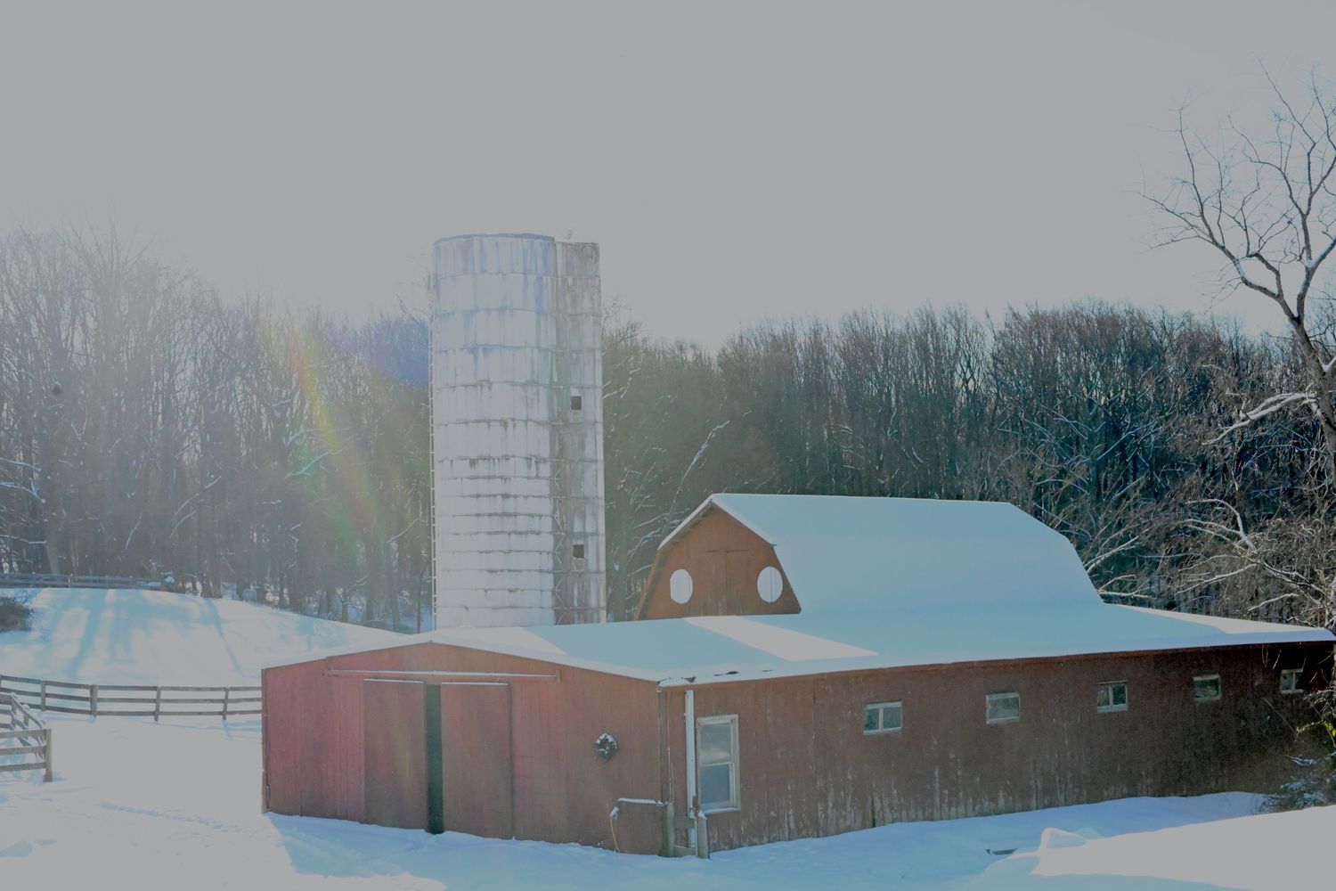 a red barn and silo covered in snow