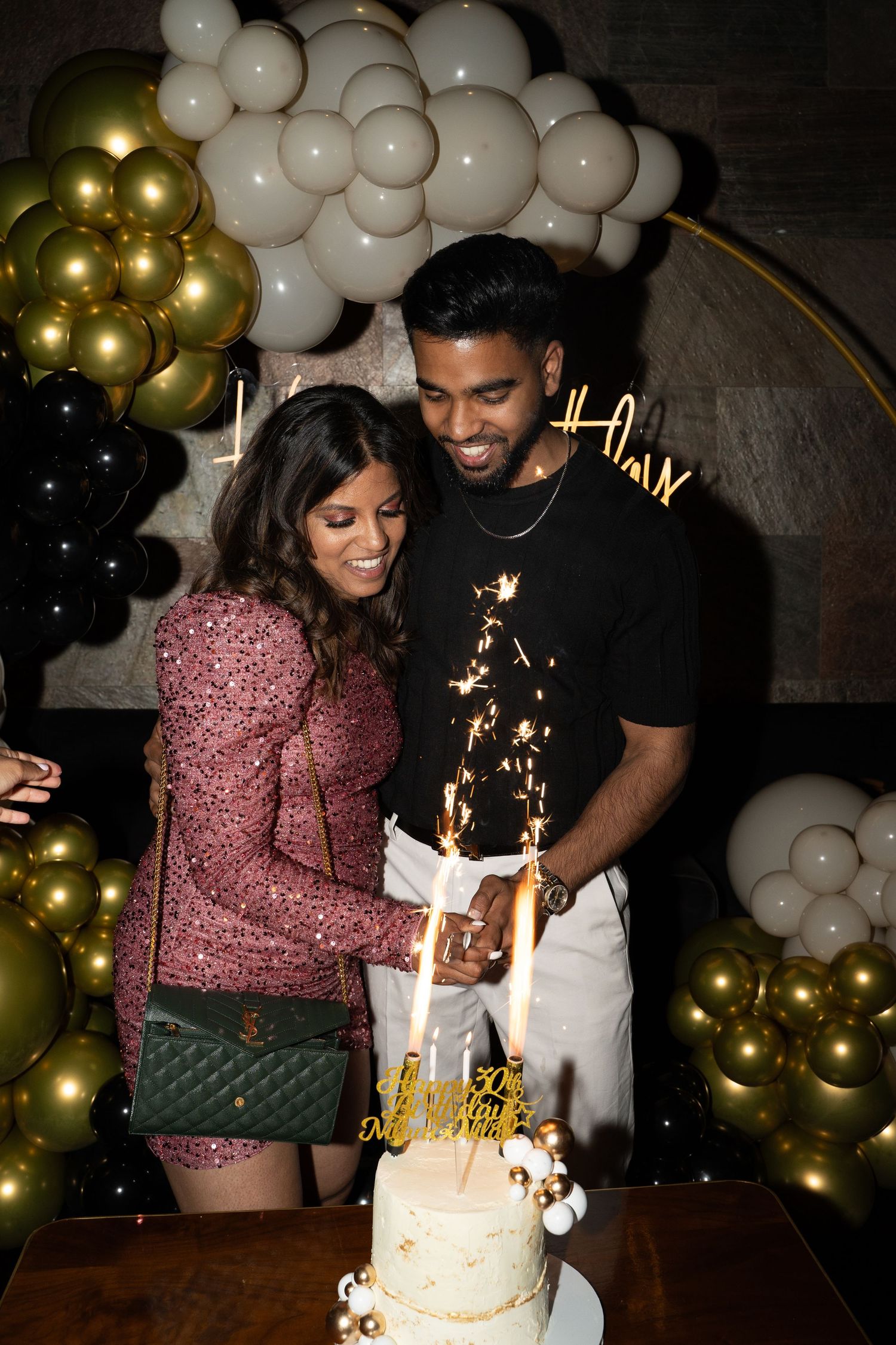 Twins celebrates with a sparkler-topped white birthday cake surrounded by gold and white balloon decorations.